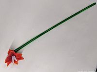Full view of red Murano glass flower with green stem against white background showing entire item length and flower detail.