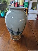 Front view of ceramic vase showing pine tree and mountain landscape glaze.