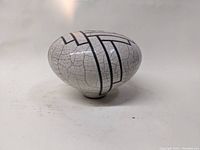 Oval Raku art pottery vase with white crackled glaze and black sgraffito geometric lines shown from side angle.
