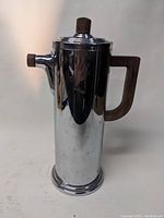 Front side view of vintage chrome cocktail shaker with walnut handle and top knob