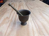 Full view of the mortar with pestle resting inside, showing shape and wooden surface background.