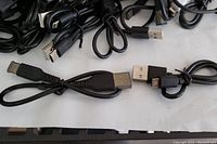 Photo showing multiple black USB-A to USB-C and USB-A to Micro USB cables coiled with connectors visible.