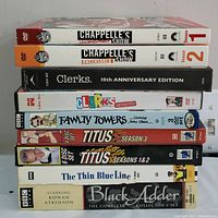 Stack of 9 comedy DVD boxsets including DVDs of Chappelle's Show Seasons 1 and 2, Clerks 10th Anniversary Edition and Uncensored, Faulty Towers, Titus Seasons 1, 2 and 3, The Thin Blue Line, and Black Adder.