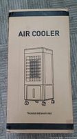 Cardboard packaging box showing an outline illustration of the air cooler with casters and text 'AIR COOLER'