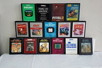Photo shows 15 Atari 2600 game cartridges arranged in three rows with clear label artwork including Enduro, Kung-Fu Master, Pitfall II, Sorcerer's Apprentice, Kangaroo, Centipede, Solaris, Warlords, River Raid, California Games, Defender among others.