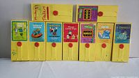 Front view of all nine yellow Fisher-Price Movie Viewing Cartridges lined up, showing colorful illustrated labels of classic animated titles and red circular buttons.