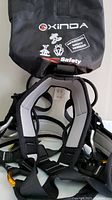 Photo showing padded shoulder straps and original storage bag with Xinda logo and industrial safety harness text.