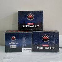 Front and sides of three sealed Gear Up 60 in 1 Survival Kit boxes showing product branding and packaging condition.