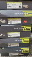 Stack of Tek Gear boot boxes in various sizes including 7, 8, 9, 10, 11, showing brand name and size labels.