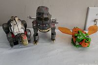 Three Dinobots in dinosaur modes: brontosaurus (left), T-rex (center), pteranodon (right)