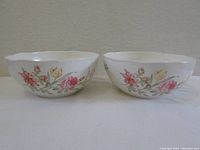 Two Wedgwood serving bowls side by side showing identical floral and butterfly pattern on exterior, ivory porcelain with scalloped rim.