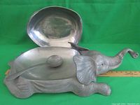 Elephant-shaped pewter serving tureen with lid removed, spoon placed inside, ruler showing length.