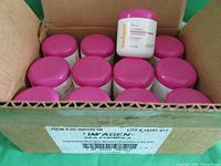 Box of 12 containers of Imagen Spa moisturizing cream with pink lids, showing the packing and arrangement.