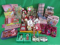 Wide view of lot showing various Christmas figurines, notepads, accessories and watches arranged on green cloth