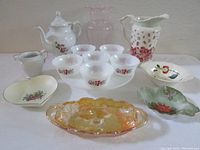 Photo of a collection of milk glass, porcelain, and glassware including cake stand, coffee pot, custard cups, pitcher, bowls, and plates.