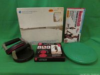 Photo shows a black and red Twist Board, green textured rubber balance disc, and Beachbody branded packaging box.