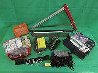 Camping gear including folding saw, machete, various ropes, and multiple first aid and emergency pouches on green background.