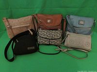 Photo of six name brand cross-body purses arranged in two rows showing colors and styles including brown, blue-gray, beige, black, and patterned bags.