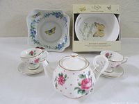 Full view of the three-piece miniature porcelain tea set with two cups and saucers, plus Limoges and Lenox bowls.