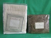 Two items sealed in plastic: a luxurious textured throw labeled 'Rose Natural Borders' in cream color, and a Pottery Barn plush faux fur sham in dark brown.