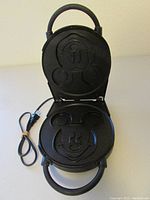 Open waffle maker showing non-stick plates shaped like Mickey Mouse face and head