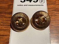 Pair of gold-tone round Chanel earrings on white notes and measurements card, viewed straight-on