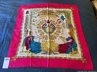 Full view of square scarf laid flat, showing magenta border and central allegorical design