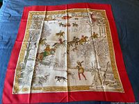 Full view of scarf laid flat showing red border and central winter hunting tableau.