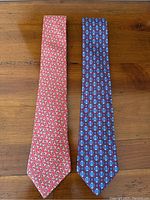 Both ties laid flat on wooden surface, red on left and blue on right