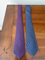 Two ties laid flat on wooden surface showing full length and patterns