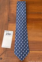 Full length of navy blue owl-patterned tie laid flat on wooden surface.