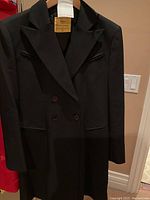 Full front view of black overcoat on hanger