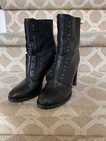 Front view of both black leather ankle boots on staircase showing toe, eyelets and heel