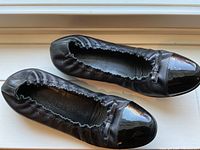 Top-down view of both flats on window sill showing elasticized topline and patent toe wear