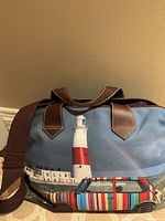 Bag front showing lighthouse and striped car print with leather handles