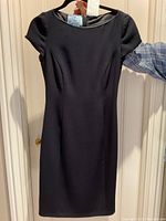 Front view of navy blue Prada dress on hanger against door