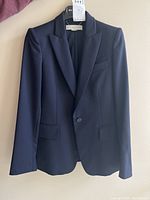 Front view on hanger showing overall fit, single-button front and flap pockets.