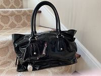 Front view of handbag showing dual rolled handles, glossy finish and overall shape.