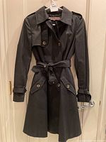 Front view of black trench coat on hanger