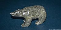 Front view of polished soapstone polar bear sculpture showing head, body and legs.