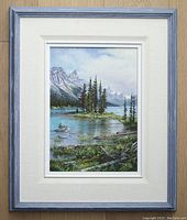Framed oil painting full view showing "Spirit Island" landscape with island, pine trees, lake and mountains, in gallery frame with linen liner.