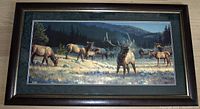 Framed wildlife print showing elk in a mountain meadow with green matting and wooden frame.