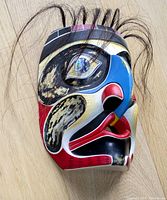 Angled front-right three-quarter view showing painted motifs, inlaid eyes and horse hair detail