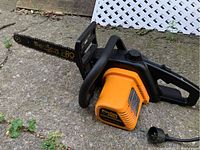 Orange and black Poulan Pro 300E chainsaw lying on ground showing full body and chain bar.