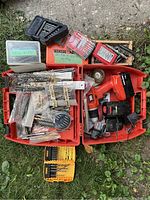 Full overview of open orange toolbox showing Black & Decker cordless drill, batteries, charger, and numerous drill bits in cases and bags.