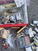 Photo showing open plastic bin with mixed electrical parts including lamp sockets, wiring, small component boxes, and assorted hardware spread around.