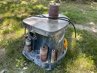 Front angle shot of unit on grass showing sanding drums stored around base and power cord draped over table