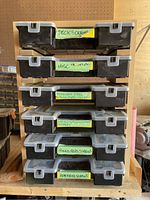 Front view of six stacked black plastic organizers labeled with contents such as deck screws, miscellaneous, stainless steel washers/hooks, lag bolts/machine screws/washers, round head screws, flathead screws
