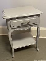 Front angled view of gray painted nightstand with drawer and curved legs