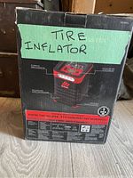 Box of the digital tire inflator showing branding and product details with handwritten label 'Tire Inflator'